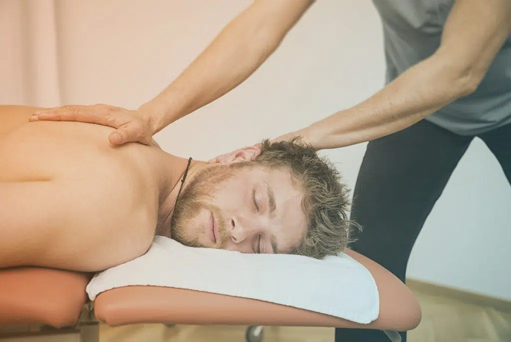 Massage therapist massaging young male upper back.