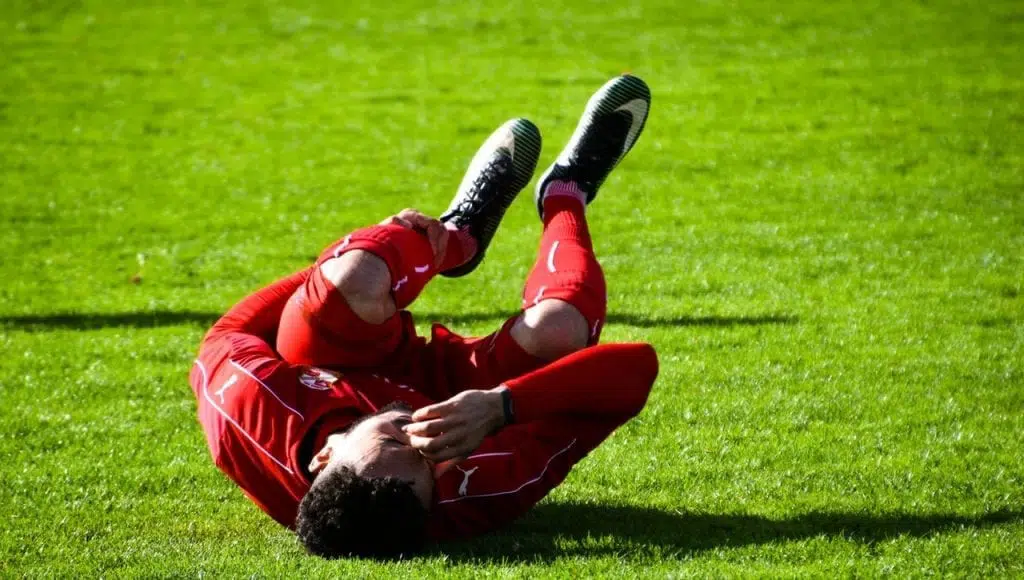 Injured soccer player crouching in the playing field.