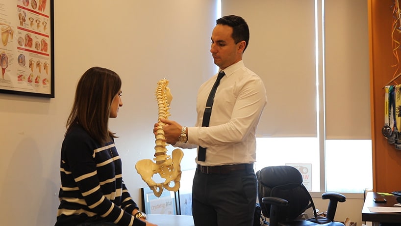 Dr. Misa Zaker showing a patient a figure of the human spine.