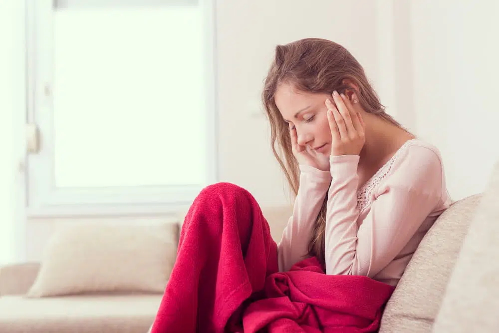 Young lady holding her head because of pain caused by fibromyalgia..