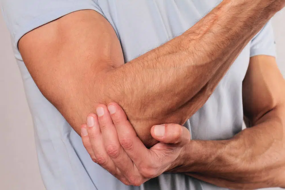 Man holding his elbow due to swelling pain from tendonitis.
