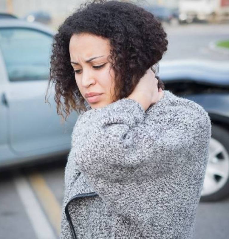 Woman holds neck due to whiplash after an auto accident.