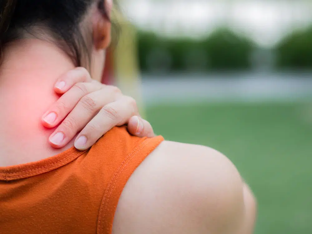 Woman holds neck because of neck pain.