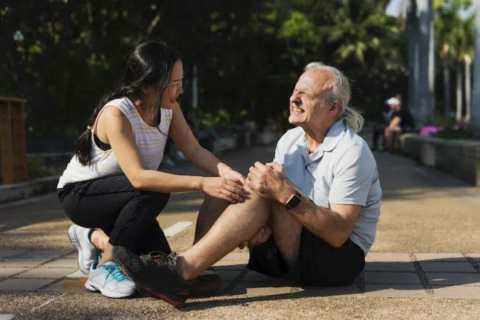Elderly man holding his knee due too knee pain from running.