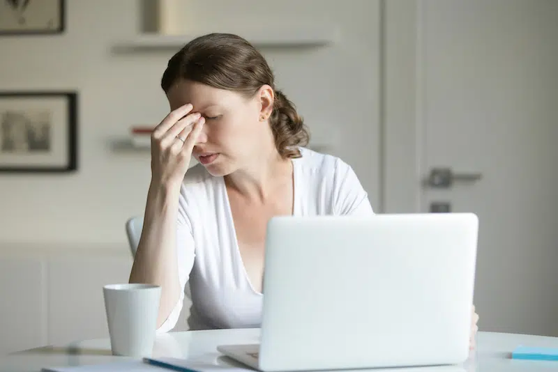 Woman on her laptop having a headache.