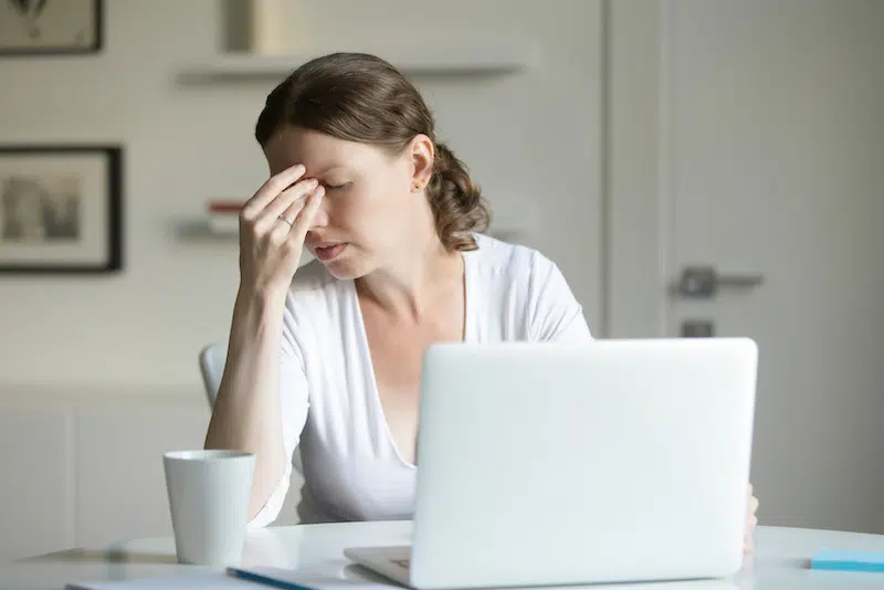 Woman on her laptop having a headache | Headache and Migraine Treatment