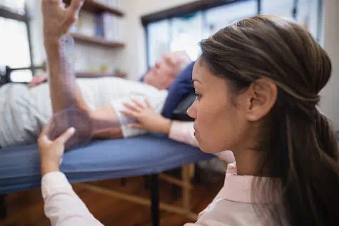 Female doctor examining a patient's elbow.