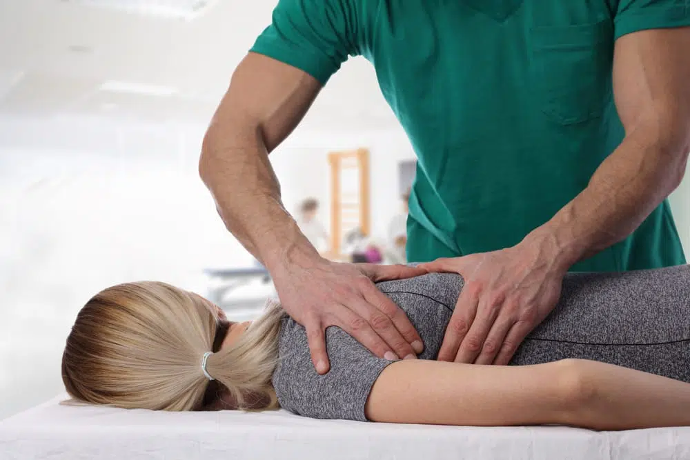 Chiropractor adjusting female patients shoulder to cure pinched nerve.