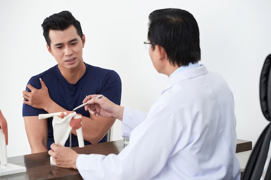 Young man talking to his doctor about his shoulder pain