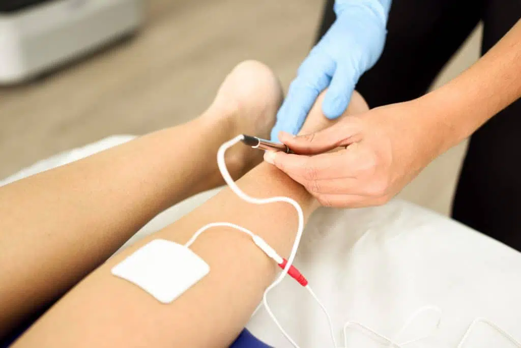 Photo of a doctor performing an electromyography test on a patient.