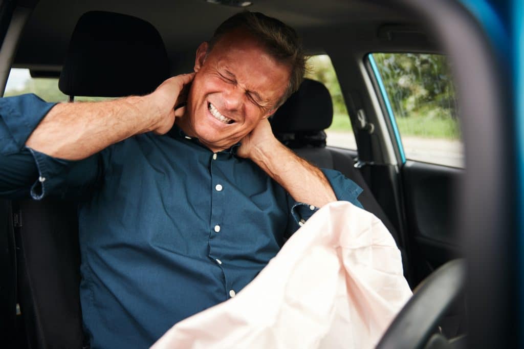 Middle aged man holding his neck after a car accident