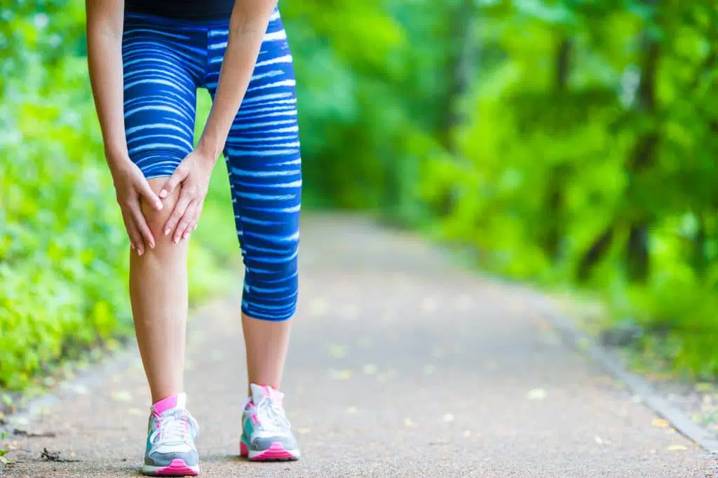 Female runner holding her knee due to a sprain.