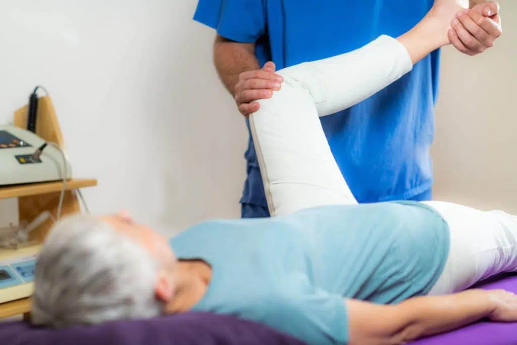 elderly woman having her knee leg stretched by a chiropractor