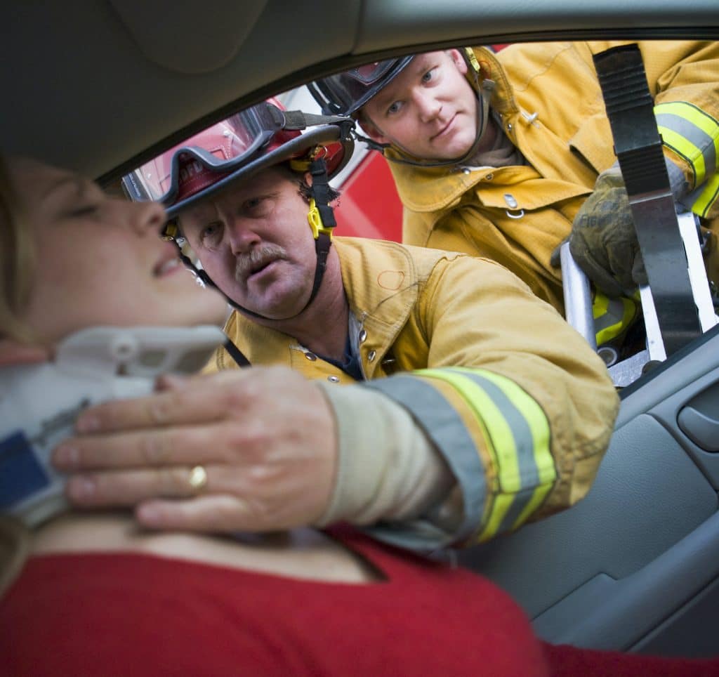 Firefighters helping an injured woman in a car.