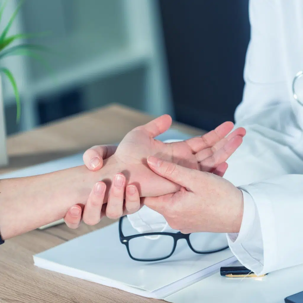 Doctor holding a woman's hand for treatment of hand and wrist pain.