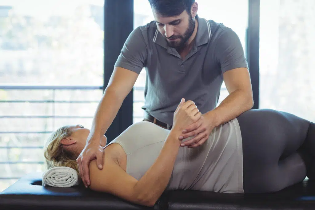 Chiropractor adjusting female patient's frozen shoulder