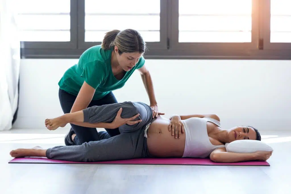 Chiropractor adjusting pregnant female patient.