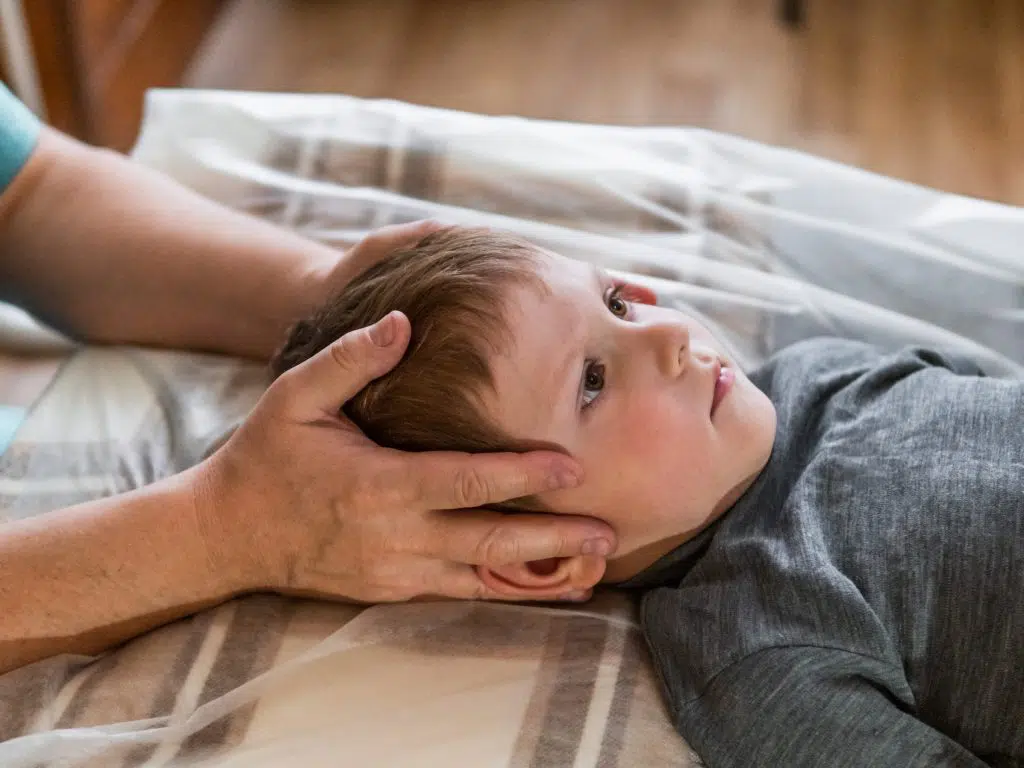 Pediatric chiropractor adjusting young boy