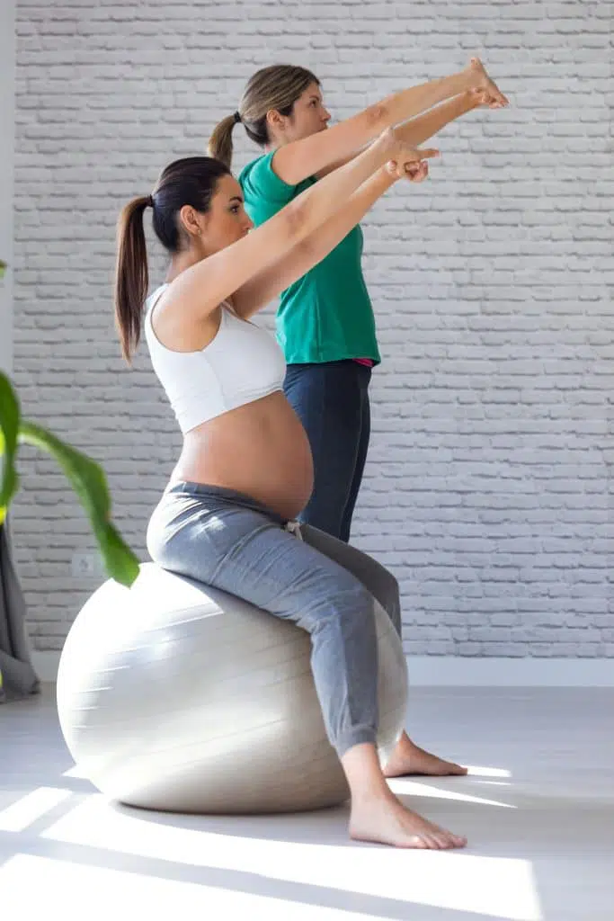 Pregnant woman stretching with physical therapist.