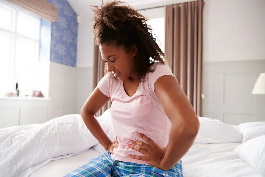 Woman sitting on her bed in pain