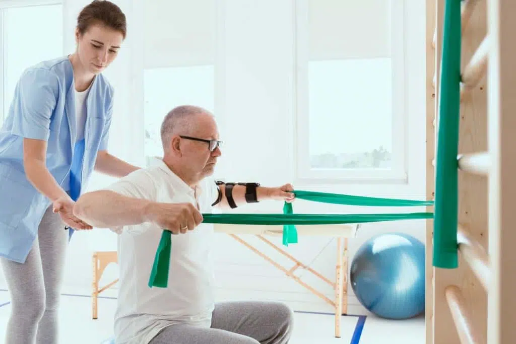Elderly man doing stretching exercises with the help of a therapist.