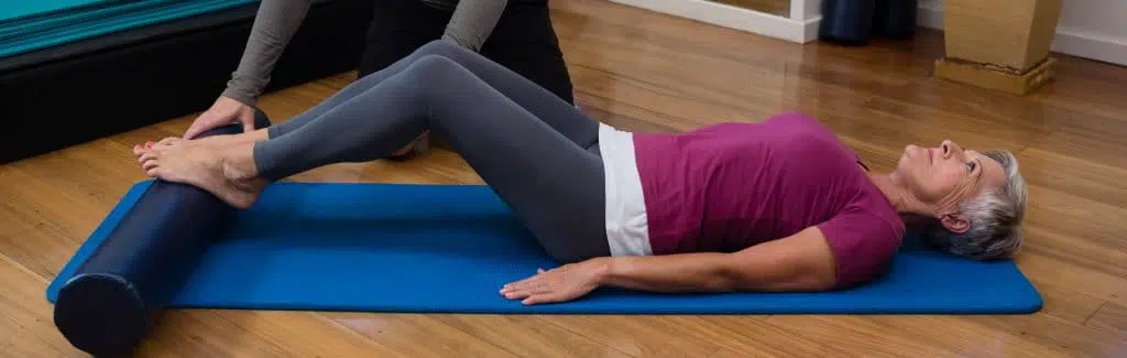 Patient stretching her hips with the help of a physical therapist.