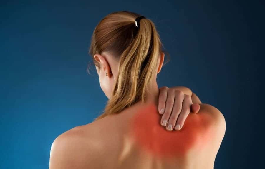 Woman holding her back due to a pinched nerve around her shoulder blade.