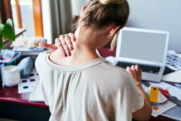 Woman suffers from neck pain after working on her computer for long time.