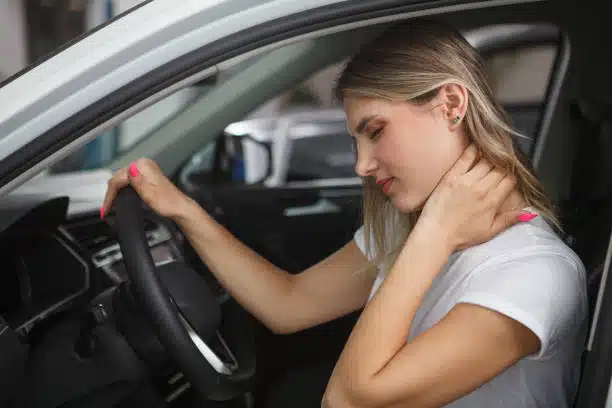 Young woman suffering from neck whiplash, after getting involved into an accident.