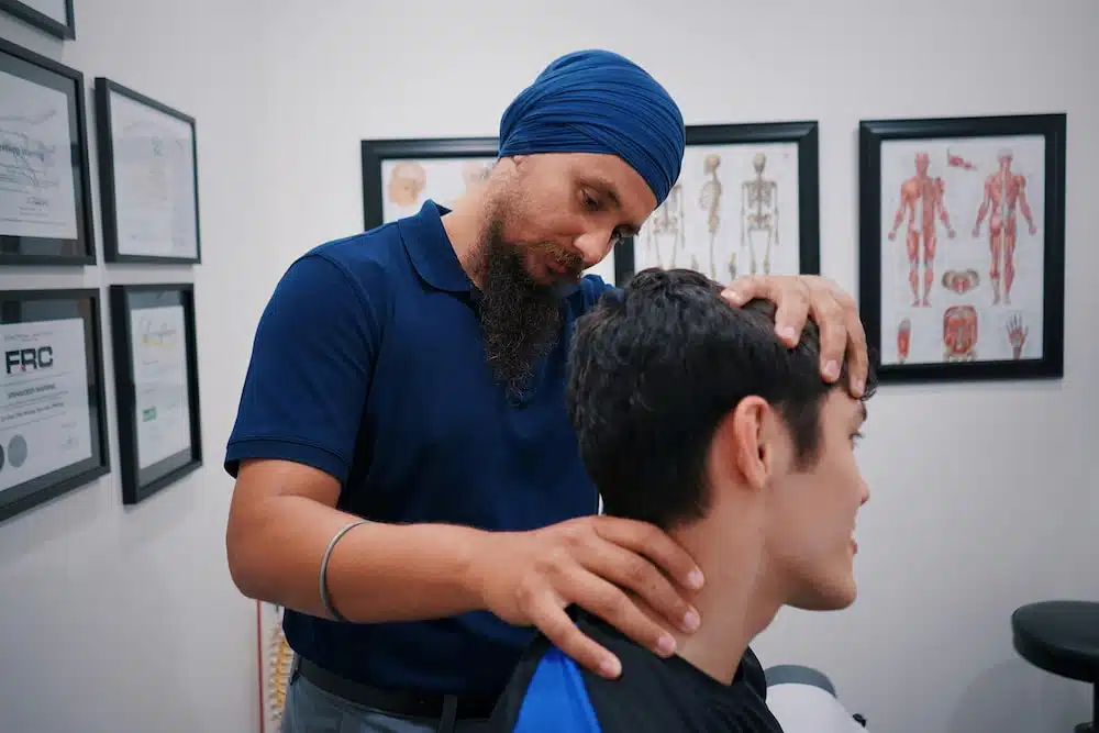 Man suffers from neck pain having an initial consultation with a chiropractor 