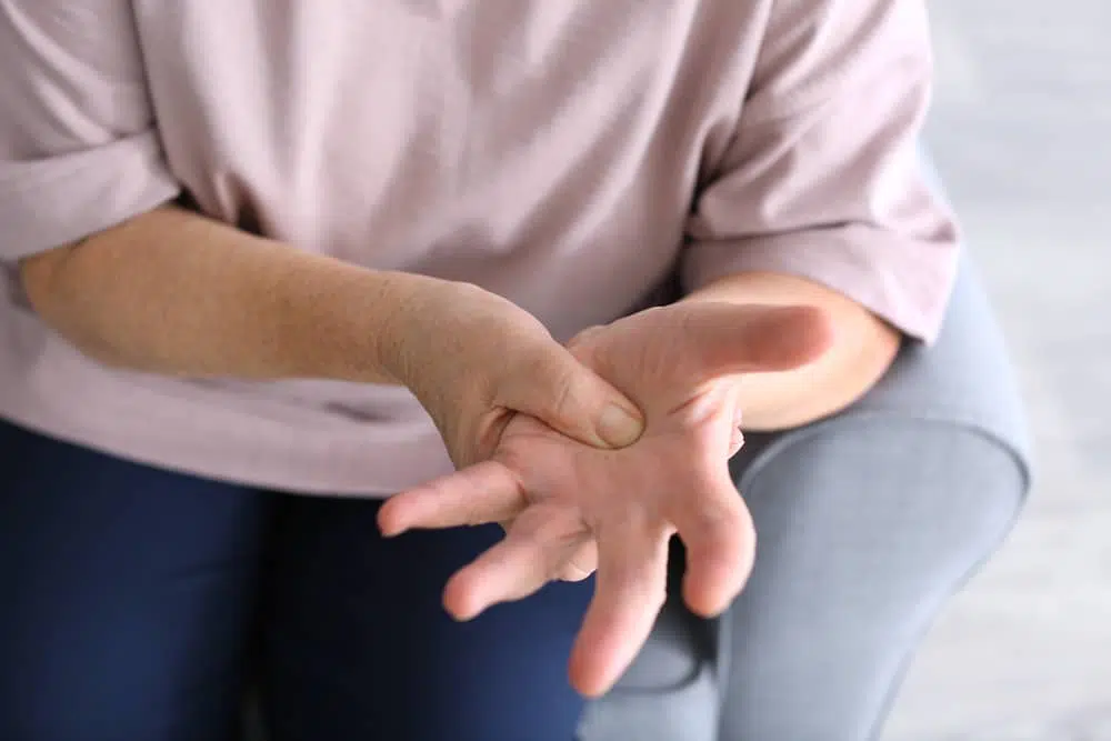 Elderly woman pinching her hand due to weakness in muscles and joints.