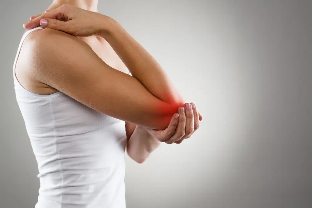 Woman massaging her elbow due to tendinitis pain.