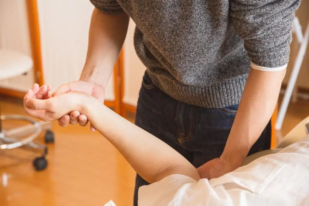 Chiropractor examining the arm of a patient- when to see a chiropractor