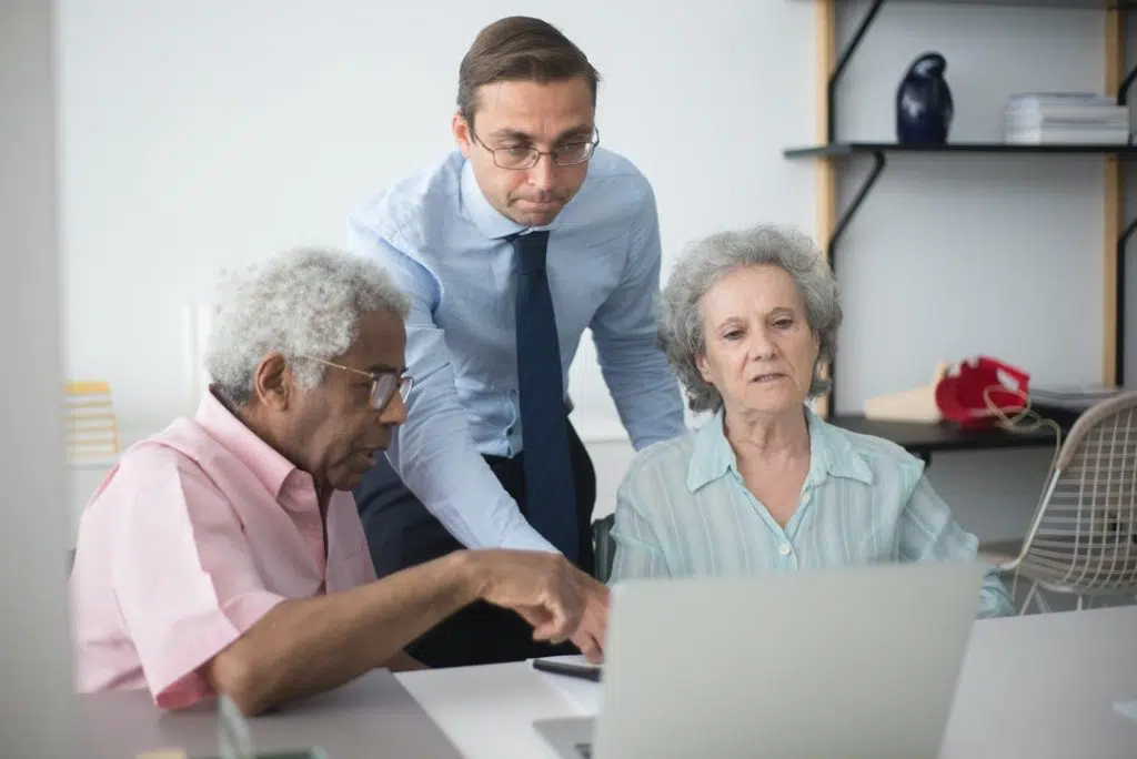 Chiropractor and couple patient discussing about the Anthem Blue Cross Blue Shield Health Insurance in the front desk of clinic