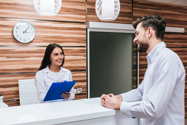 Chiropractor discussing the Cigna Health Insurance to the patient at reception desk of the clinic
