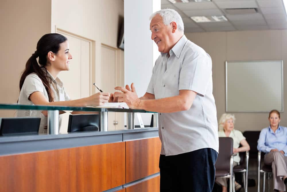 Front desk clerk and patient discussing about the health insurance benefits for chiropractic care