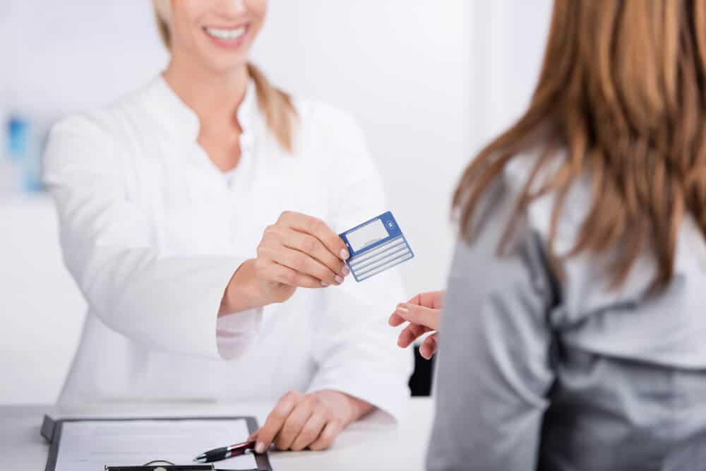 Patient handling her health insurance card to the Physician