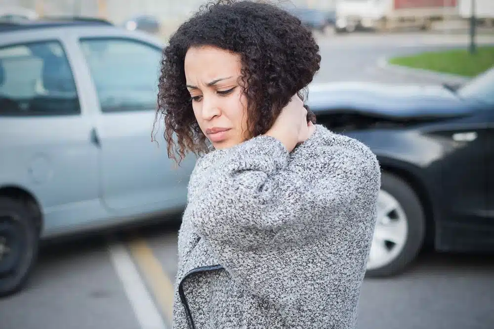 Woman holds neck due to whiplash after an auto accident.