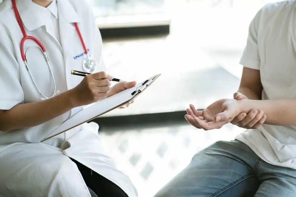 Man suffering from intense hand pain getting a check up evaluation from the chiropractor.