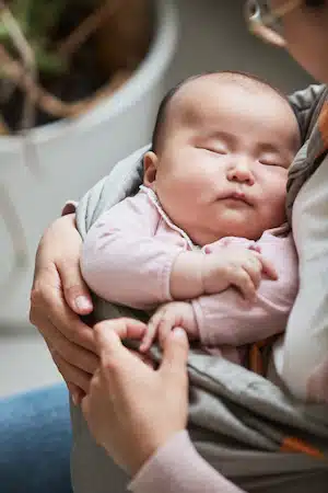baby comfortably sleeping on mothers arm after chiropractic care therapy