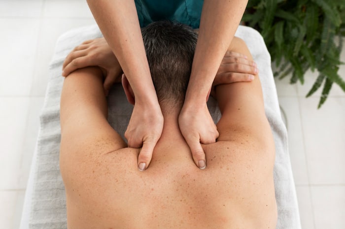 Massage therapist doing Shiatsu Massage on young male.