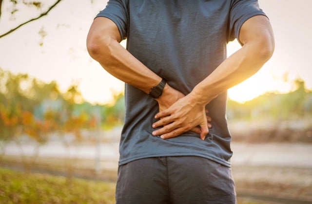 young man has muscle injury and a lower back pain during outdoor exercise