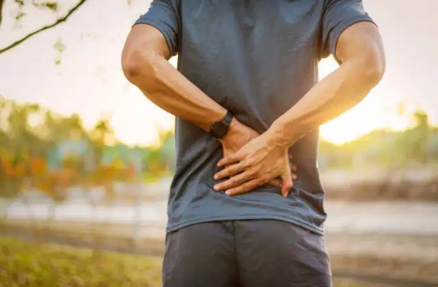 young man has muscle injury and a lower back pain during outdoor exercise