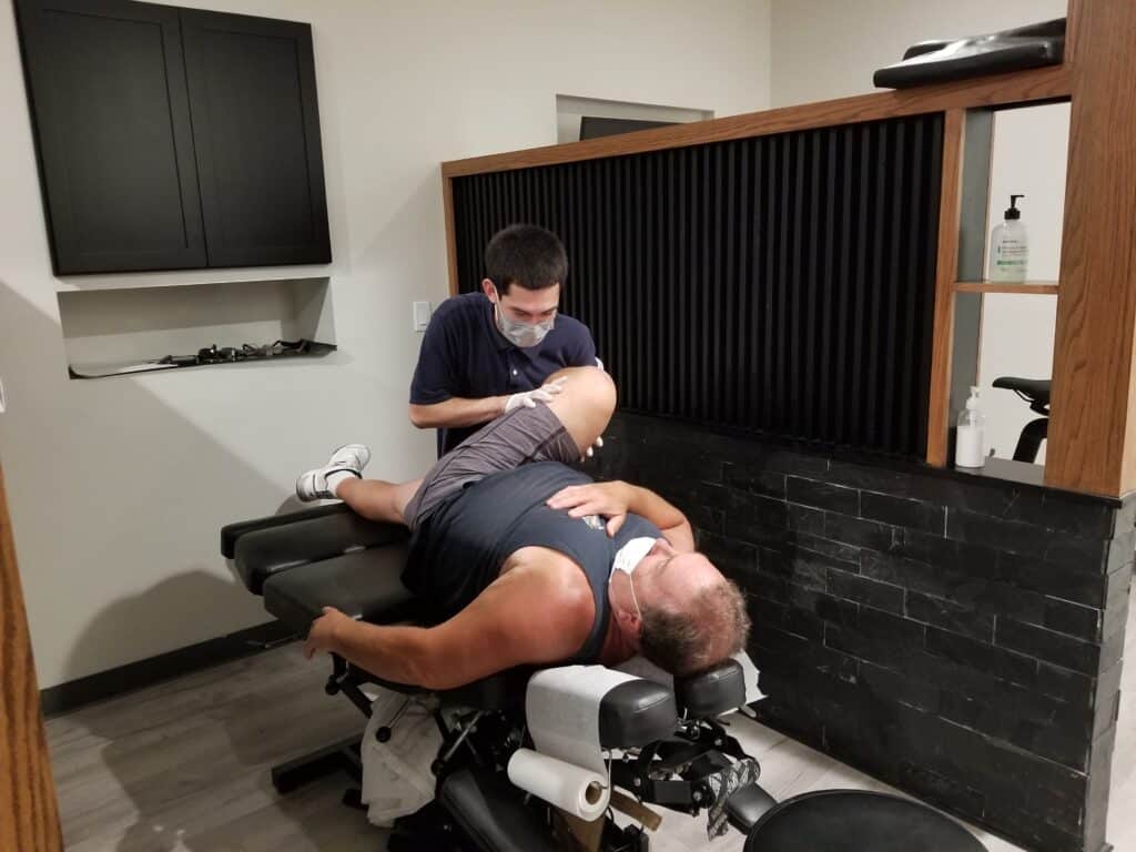 Chiropractor helping a female patient stretch for muscle tear treatment.