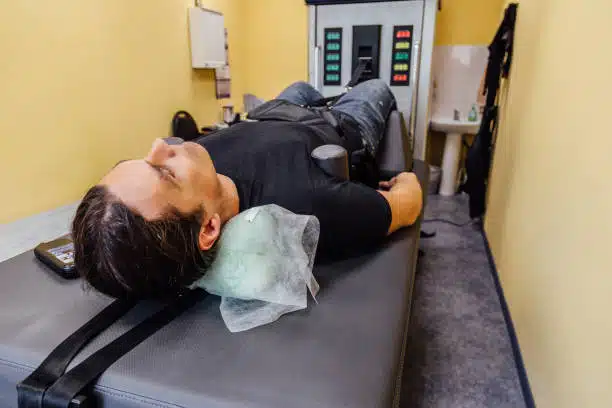 Man at non-surgical spinal decompression procedure in chiropractor clinic.