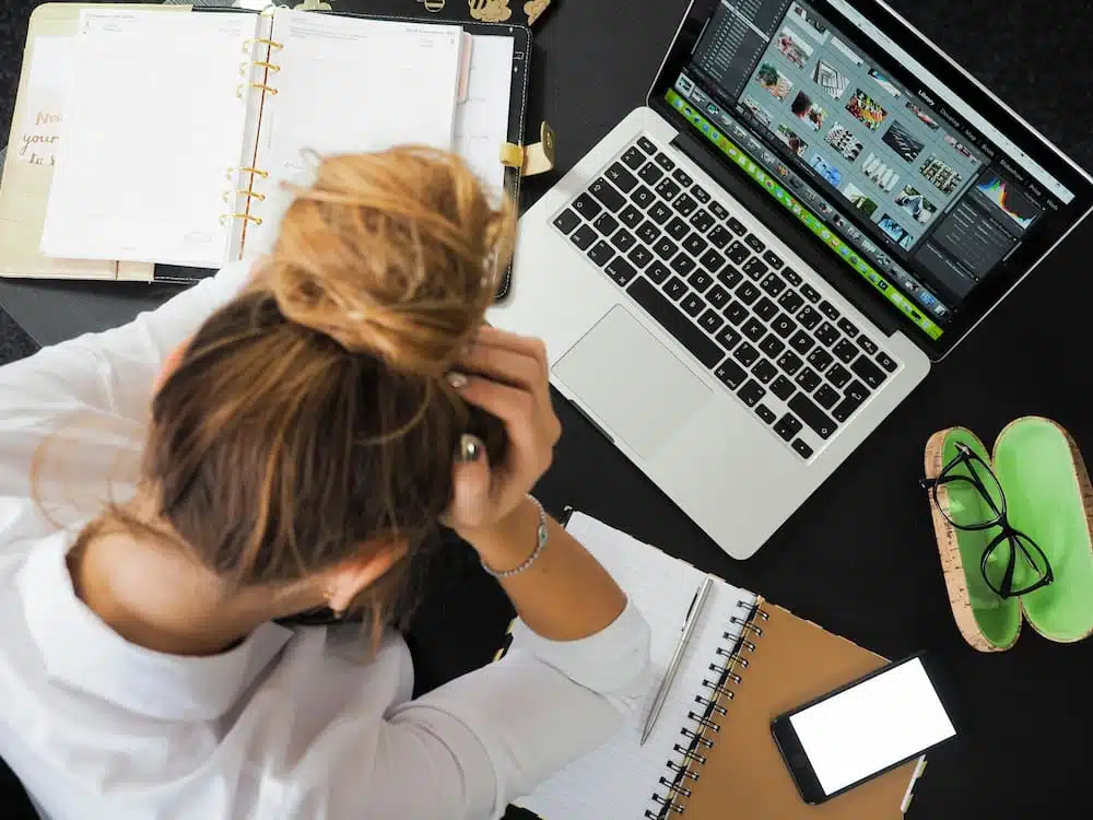 woman feeling stressed with work experiencing migraine while in front of her laptop