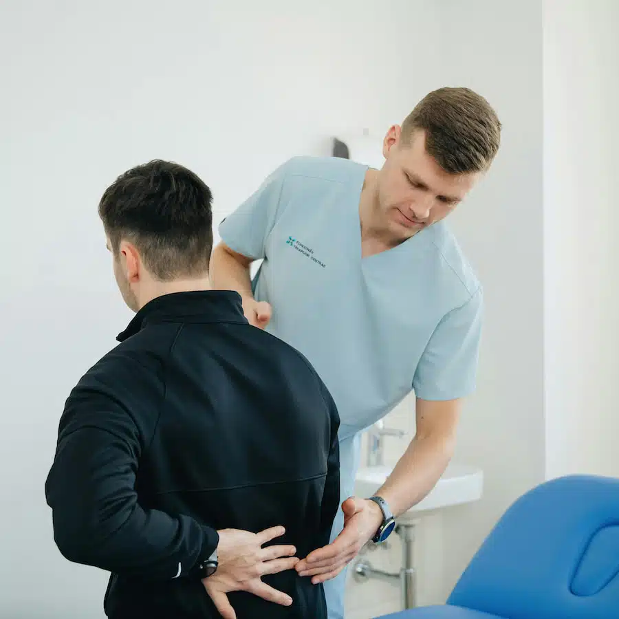 Man suffers from back pain having a check up with a chiropractor