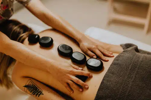 woman receiving massage on the back with hot stones