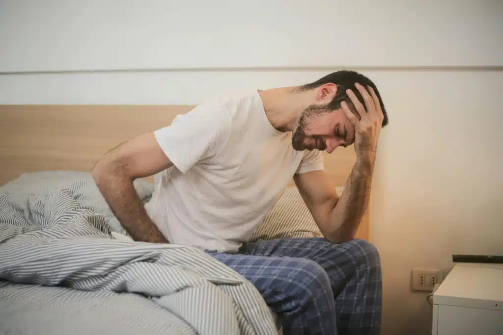 Young man in sleepwear suffering from headache in morning
